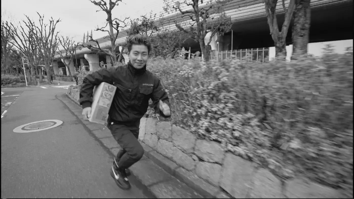 配送ボックスを抱えて走るドライバー